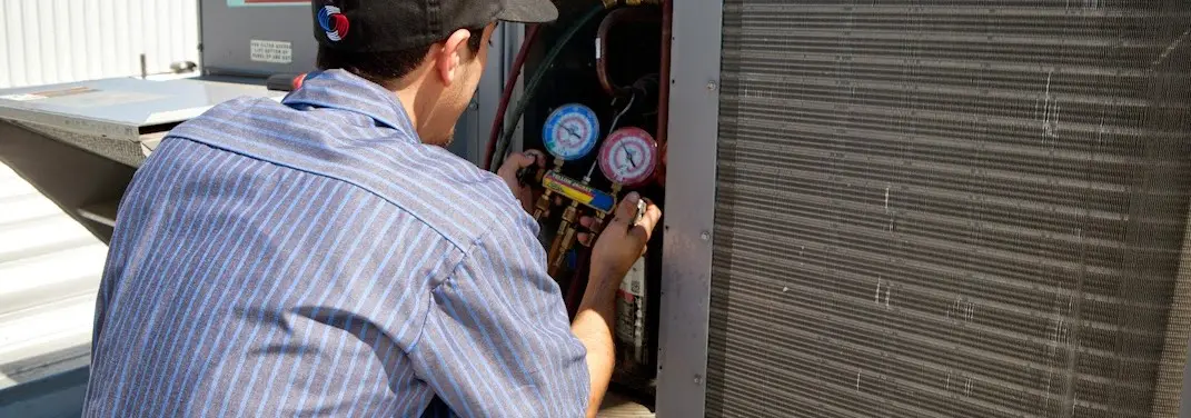 HVAC technician servicing a condenser unit in Newman