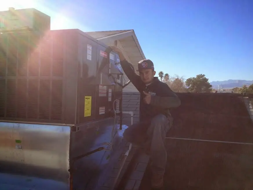 HVAC technician performing AC Tune-Up on a rooftop unit in Newman